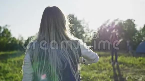 夏天穿着蓝色牛仔裤和白色运动鞋的年轻女子在高山的草地上朝太阳扔飞盘视频的预览图