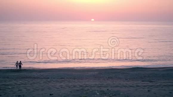 快乐的一对情侣在海水中奔跑背景是美丽的日落视频的预览图