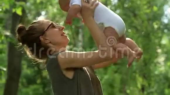 美丽的女人高高举起她可爱的婴儿开始微笑着转过身来视频的预览图