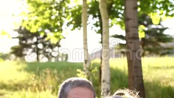 快乐的祖父母坐在草地上的公园里视频的预览图