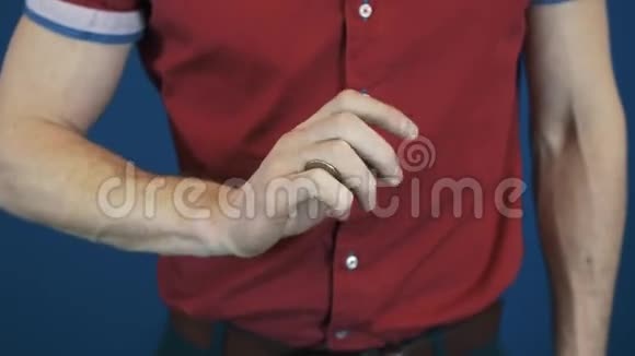 用手指把穿红衬衫的魔术师快速抛硬币视频的预览图