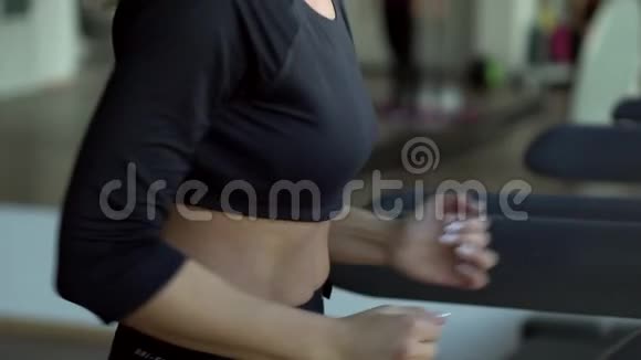 年轻女子在健身房的跑步机上跑步慢动作视频的预览图