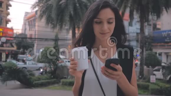 有智能手机和咖啡的女人在城里散步斯特迪卡姆视频的预览图