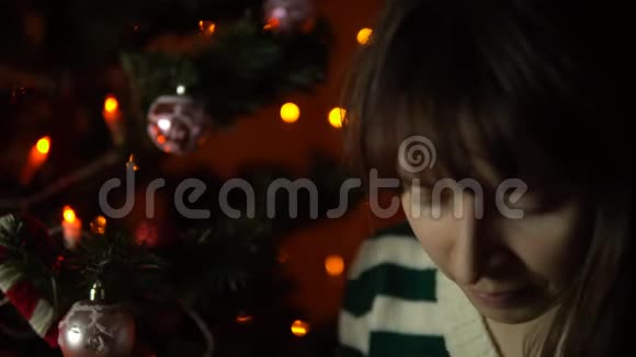 年轻女子在圣诞树下打开一个礼盒视频的预览图