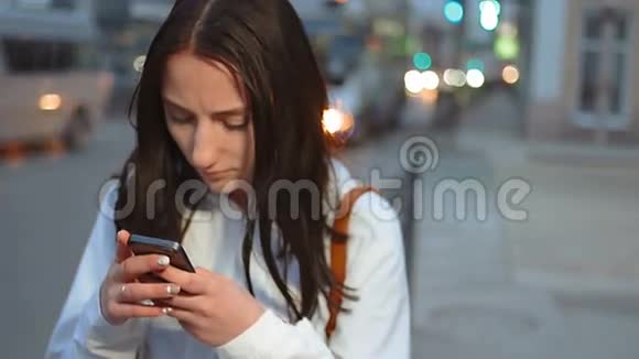 夜间街道上移动汽车背景模糊的青年女子手机短信手持镜头视频的预览图