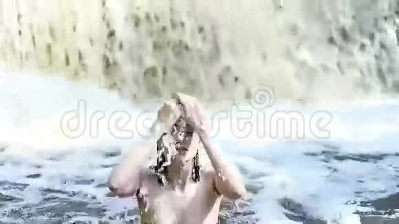 美丽的女人穿着泳衣在瀑布里洗澡视频的预览图