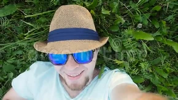 快乐男人躺在公园的草地上自拍视频的预览图