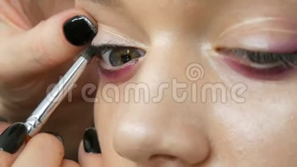 女化妆师造型师用年轻模特的特殊化妆画笔使化妆时尚粉红烟熏的眼睛视频的预览图