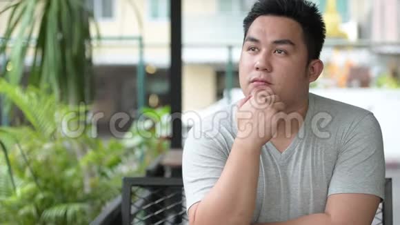 年轻英俊的超重亚洲男人在咖啡店放松视频的预览图