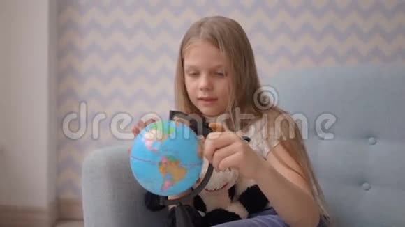 可爱的小女孩坐在沙发上拿着一个小地球仪转动着视频的预览图