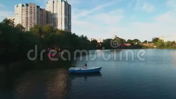 美丽的女孩坐在湖上的船上视频的预览图