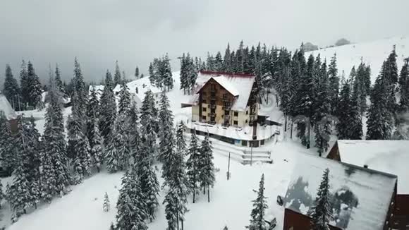 山上森林中白雪覆盖的木屋的鸟瞰图视频的预览图