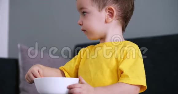 小可爱的孩子坐在一张桌子旁吃自己的燕麦片孩子吃得很自愿快乐童年的概念视频的预览图