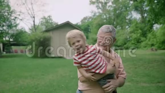 4祖父在夏天把孙子背在大自然中视频的预览图