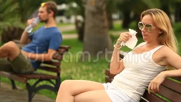 人们坐在城市公园的长凳上由于炎热而精疲力竭视频的预览图