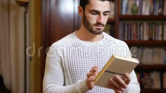 英俊的年轻人在家里客厅里看书视频的预览图
