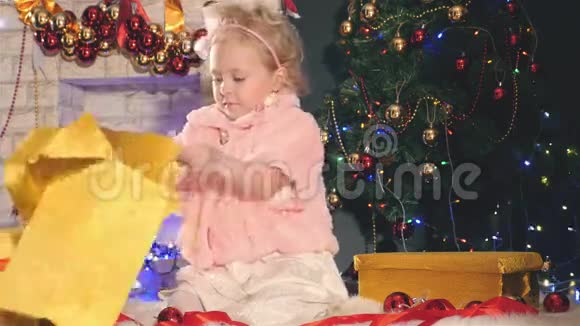 可爱的小女孩打开礼盒靠近装饰圣诞树视频的预览图