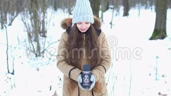 在白雪皑皑的树林里一个长着棕色长发女孩带着复古相机她微笑着视频的预览图