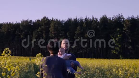 母亲父亲和儿子在油菜地跳舞和玩耍视频的预览图