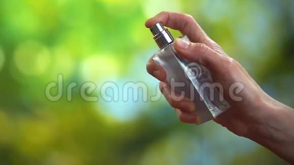 女手在绿色背景上喷洒香水慢动作高清视频视频的预览图