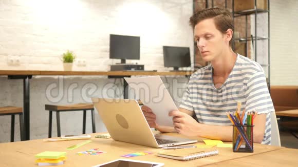 年轻设计师在洛夫特办公室的办公桌上阅读论文视频的预览图