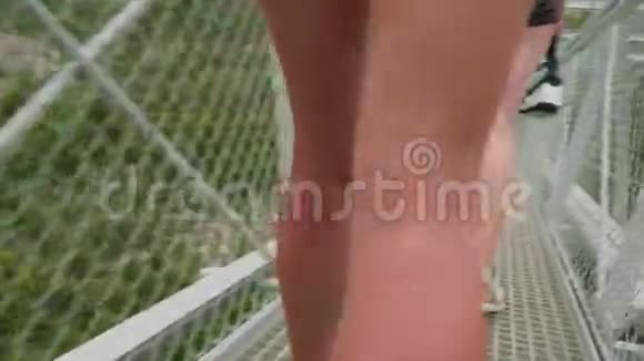 穿着运动鞋的白色女性运动腿近距离观看高山上的悬空格子桥视频的预览图