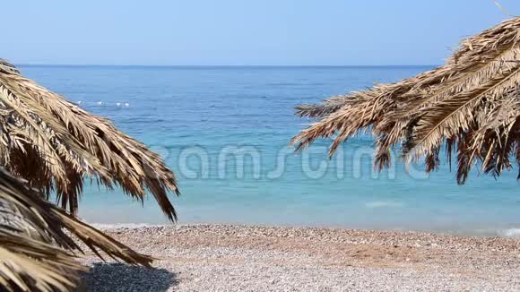 粒沙热带海滩碧海浪洗岸黑山海滩用棕榈树做成的伞视频的预览图