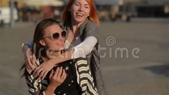 两个年轻的女朋友在美丽的城市街头嬉笑散步在度假时捎带着小朋友视频的预览图