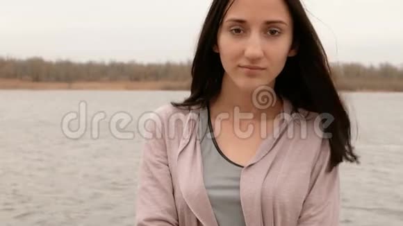 年轻漂亮的女孩伤心地呆在河边她伤心地蝙蝠开始微笑视频的预览图