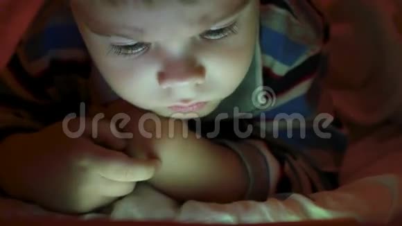 一个小男孩在深夜的平板电脑里看动画片视频的预览图