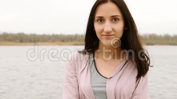 江边穿着针织夹克的美女摆姿势的肖像视频的预览图