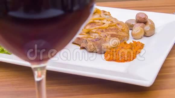 一杯红酒和牛排放在一盘西红柿上视频的预览图