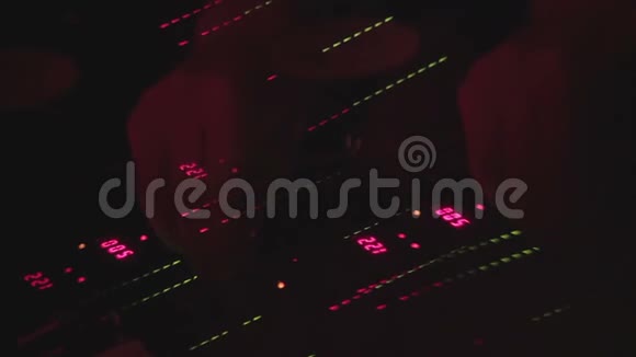 手在控制台上切换控制DJ在夜总会的聚会上混合音乐视频的预览图