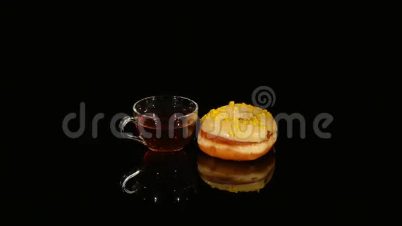 杯茶和黄釉甜甜圈在黑色背景上旋转视频的预览图