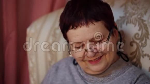 一位戴眼镜的老妇人坐在椅子上微笑着视频的预览图