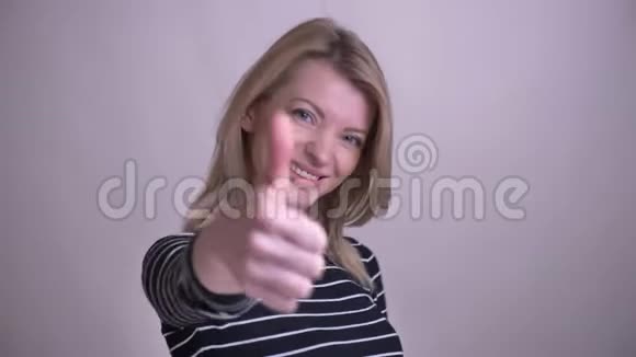 一幅成年白种人金发美女的特写照片她竖起大拇指微笑着看着摄像机视频的预览图