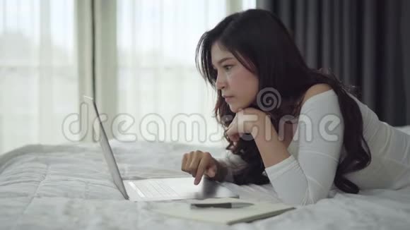 令人惊讶的女人在床上使用笔记本电脑视频的预览图