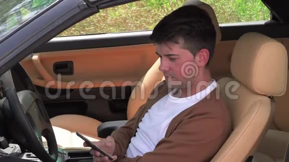一个年轻人坐在破车里打电话视频的预览图