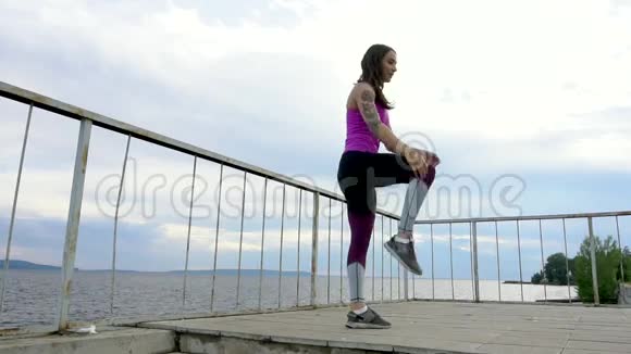 河堤上的健身女孩做伸展运动慢动作视频的预览图