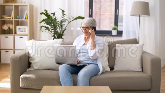 带手提电脑的老年女性打智能手机视频的预览图