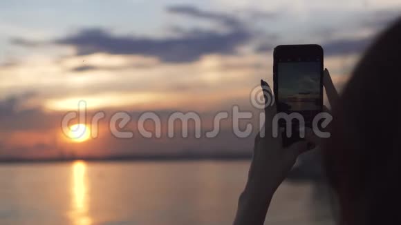女孩用手机相机拍摄日落照片视频的预览图
