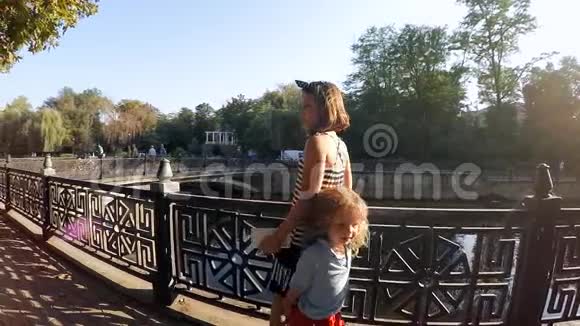 下面的动作孩子们在河边的城市公园里散步视频的预览图