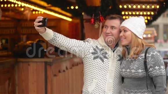 技术和人的概念圣诞快乐一对穿暖衣服的游客带着智能手机视频的预览图