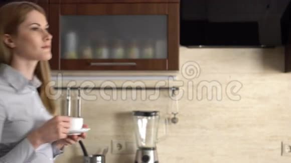 美丽的女商人站在她的厨房微笑在家开心轻松喝咖啡视频的预览图
