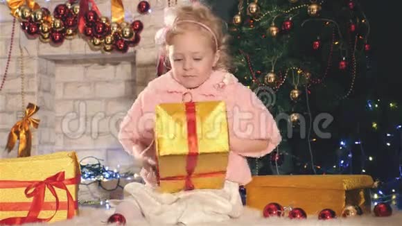 可爱的小女孩打开礼盒靠近装饰圣诞树视频的预览图