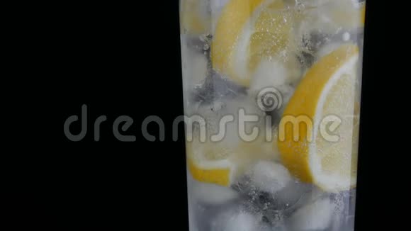 用冰块和冷苏打切好的柠檬在一个长长的杯子里黑色背景的近景新鲜柠檬酱视频的预览图
