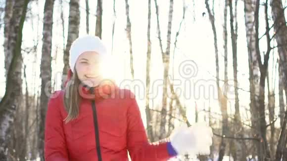 美丽的年轻女子在阳光明媚的冬季公园里打雪球玩得开心微笑慢动作视频的预览图