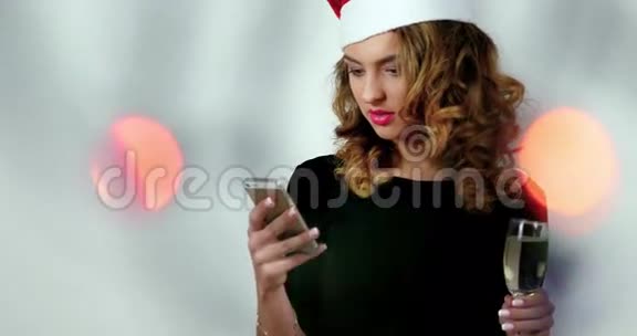 女模特在照相馆里用的是手机女模特戴着圣诞老人帽子拿着一杯香槟视频的预览图