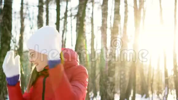 美丽的年轻女子在阳光明媚的冬季公园里玩雪球玩得开心微笑慢动作视频的预览图