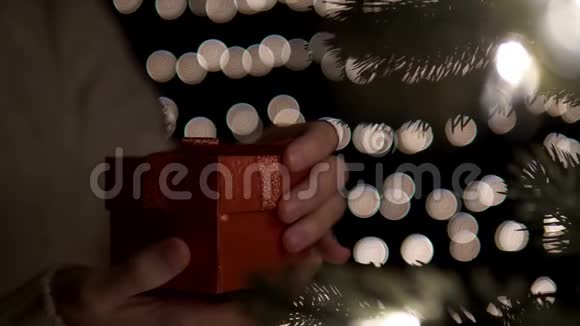 boke灯光背景下女性打开红色圣诞礼盒视频的预览图